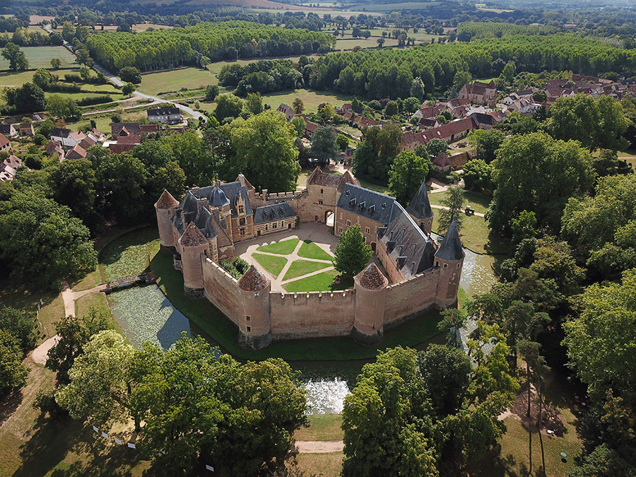 Vue aérienne du Château d'Ainay-le-Vieil avec ses remparts moyenâgeux protégeant un logis renaissance.